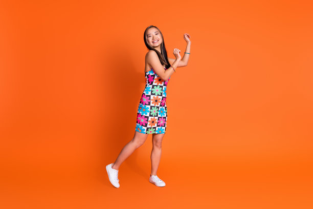 乐观可爱的女人的全尺寸照片穿花印花裙跳舞在夏季聚会上有乐趣孤立的橙色背景图片下载