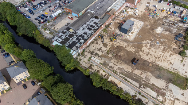无人机拍摄的利兹市中心运河边施工的照片显示，挖掘机正在清理建筑工地，准备在建筑工地上进行施工工作图片下载