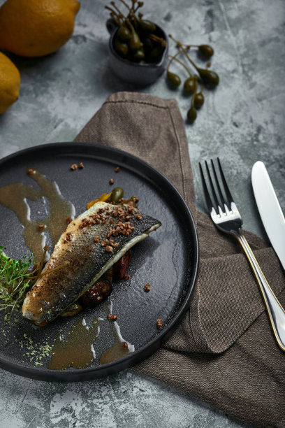 烤鲈鱼配茄子和酸橙。水平俯视图，俯视图。复制空间，灰色混凝土大理石背景，柔和的光线。美食时尚照片。图片下载