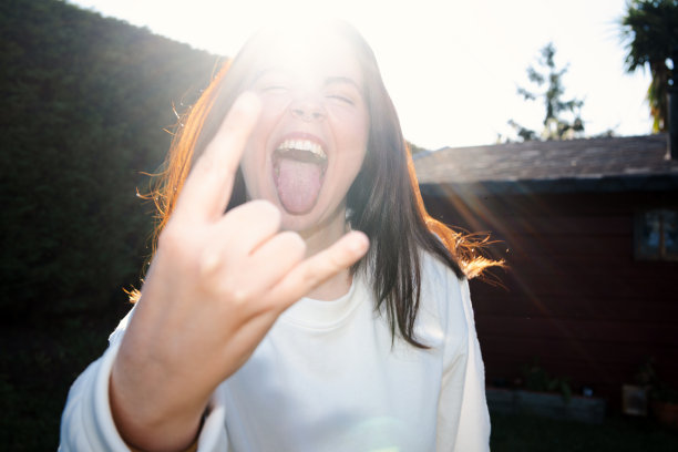 一个女孩做摇滚手势的前闪光灯照片图片下载