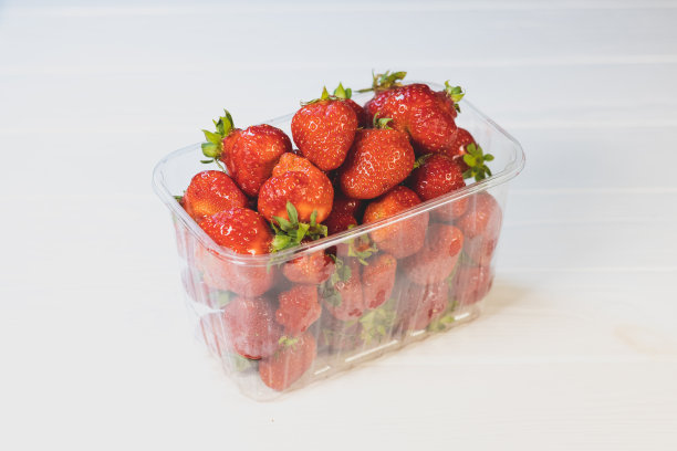 新鲜的红草莓装在白色背景的包装里。图片下载