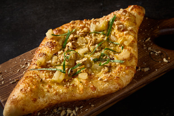 这是一张特写侧面照片，捕捉了阿贾德里亚人khachhapuri的复杂细节，在一块质朴的木板上点缀着梨、坚果和奶酪图片下载