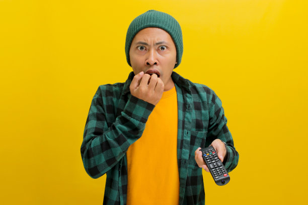 惊讶的年轻亚洲男子在电视上看到令人震惊的新闻图片下载