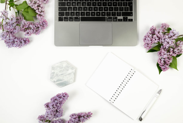 白色背景上紫色丁香花的俯视图。笔记本电脑，白色笔记本，钢笔和大理石托盘。图片下载