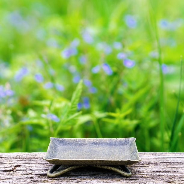 古旧木桌上的青铜低烛台，与草地相映成趣，展示创意手工制品图片下载