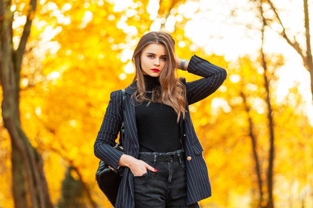 美丽的商务女性，红唇，时尚优雅的西装，外套，毛衣，背包，漫步在色彩鲜艳的金色秋叶的大自然中图片下载