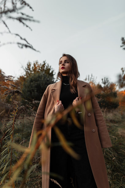 优雅美丽的女人，穿着时髦的秋色大衣和毛衣，漫步在草丛中图片下载