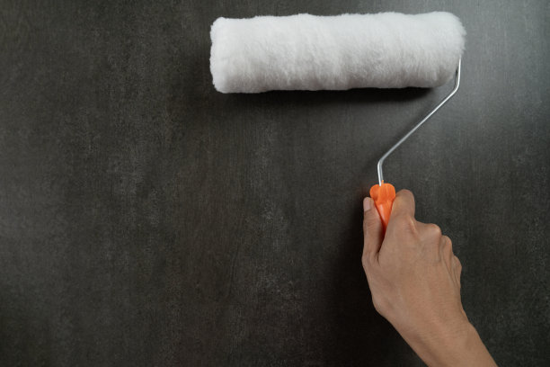 手工工人拿着毛笔在黑色背景的房子上作画，diy和修补的概念图片下载