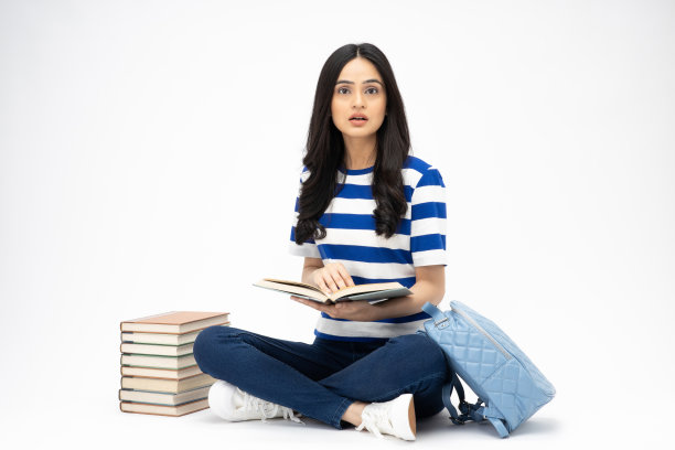 全身尺寸的年轻女孩读书坐在地板上穿着牛仔裤牛仔粉t恤鞋孤立在白色背景股票照片图片下载