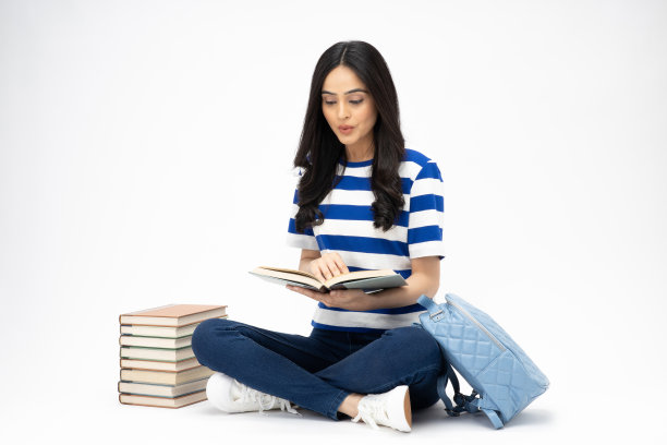 全身尺寸的年轻女孩读书坐在地板上穿着牛仔裤牛仔粉t恤鞋孤立在白色背景股票照片图片下载