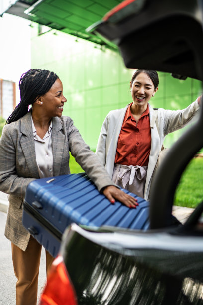 两个女商人在汽车后备箱收拾行李图片下载