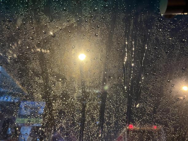 透过被雨水覆盖的窗户，可以看到路灯的照片。图片下载