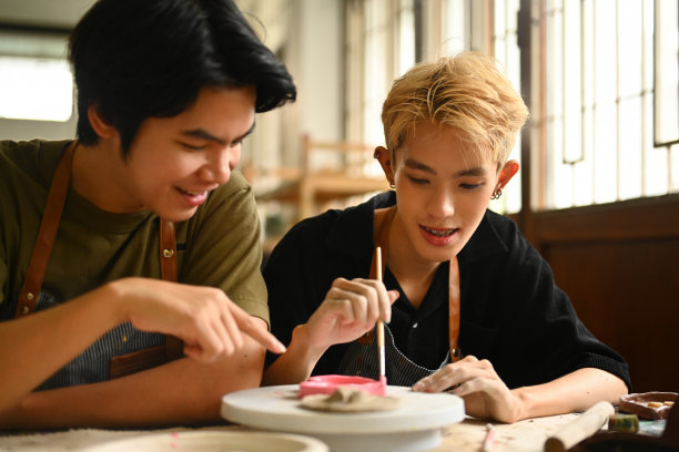 两个学生在美术课上愉快地合作，一起画一件陶瓷作品。这张照片捕捉了他们在创造性环境中的参与和团队合作图片下载