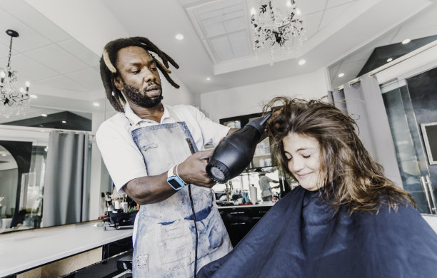 一个不到十岁的女孩在美容院由一位黑人男理发师理发图片下载