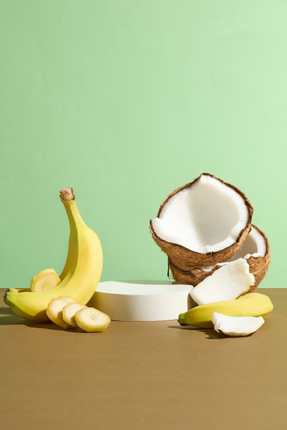 绿色背景的正面照片，黄色香蕉和热带椰子陈列在棕色的台面上，中间是一个空的讲台。展示产品或设计的空白空间图片下载