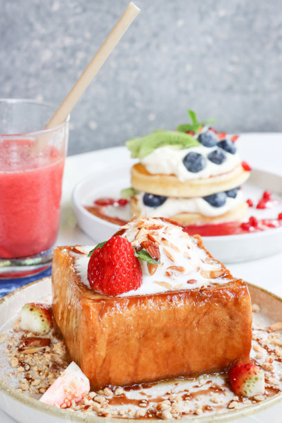 特写图片白色盘子金色厚切法国吐司，香草冰淇淋，草莓和烤杏仁片，美式煎饼与鲜奶油和新鲜水果，一杯草莓和西瓜奶昔与饮料，户外用餐场景图片下载