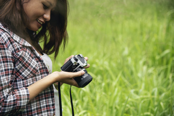 近距离的手亚洲妇女看数码单反相机复古电影风格拍照。专业女摄影师在户外看照片。年轻女子在绿色自然公园拍摄照片图片下载