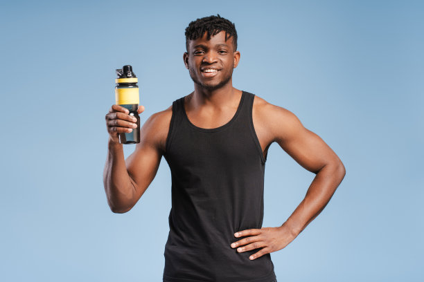 微笑英俊的年轻非裔美国男运动员穿着黑色制服拿着水瓶图片下载