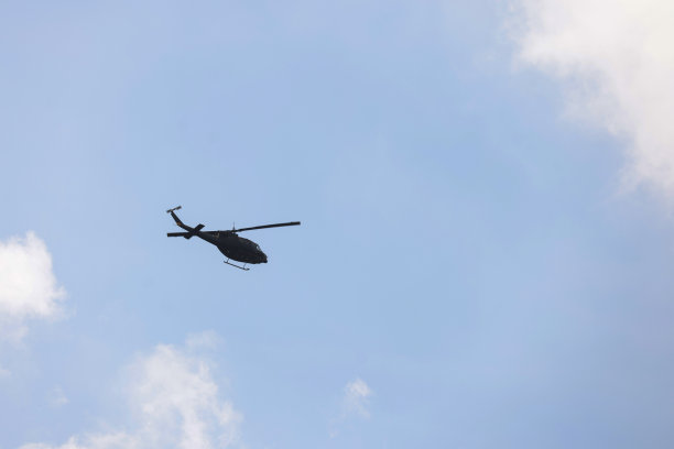 军用直升机在夕阳下飞行的照片。在晴朗的蓝天上驾驶直升飞机图片下载