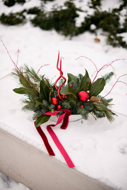 用冷杉枝装饰的花束放在一个白色的盘子里，上面有红色的树玩具和粉红色的红丝带图片下载