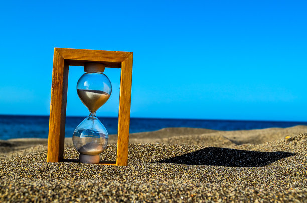 沙滩上的沙滩计时器以海洋为背景图片下载