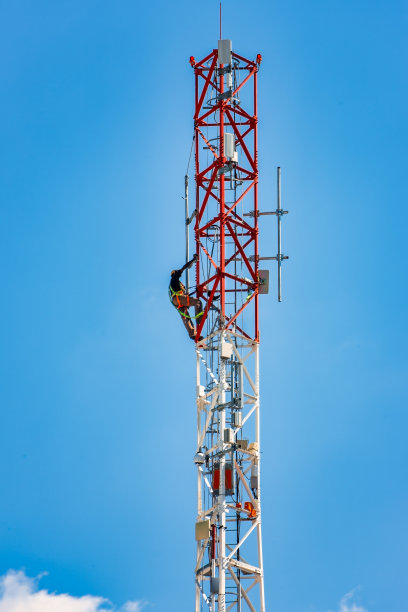 技术人员在蜂窝塔天线上工作，晴朗的天空背景图片下载