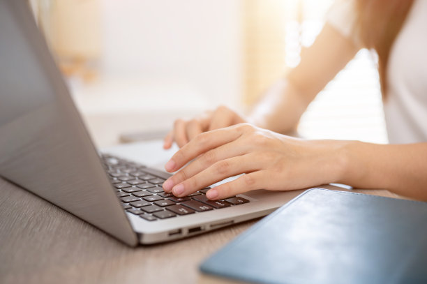 一个女人在她的笔记本电脑上工作，在笔记本电脑键盘上打字的特写照片。图片下载