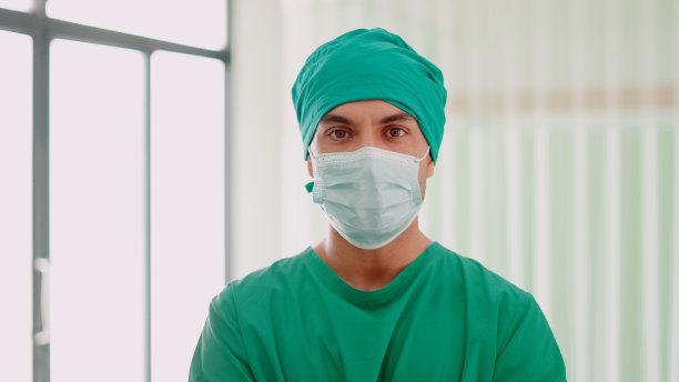 有技术和专业知识的男医生或外科医生穿着手术服站在手术室准备手术，看着镜头。在现代医院工作的医疗专业人员或护士。医疗保健。医疗肖像。图片下载