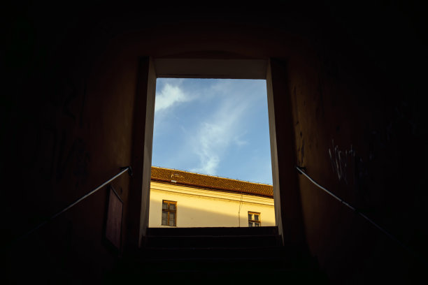 抽象照片的一种摆脱困境的方式，天空和旧房子的一部分在黑暗的窗户或门口，从黑暗到光明图片下载