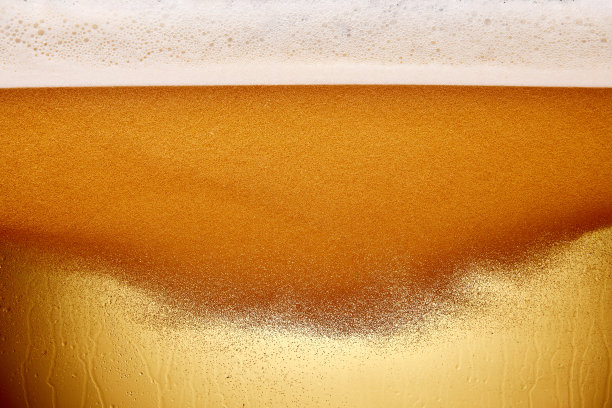 啤酒龙头将泡沫啤酒倒入透明玻璃杯的特写镜头。啤酒颜色浅，有气泡。变形的照片。抽象的背景。图片下载