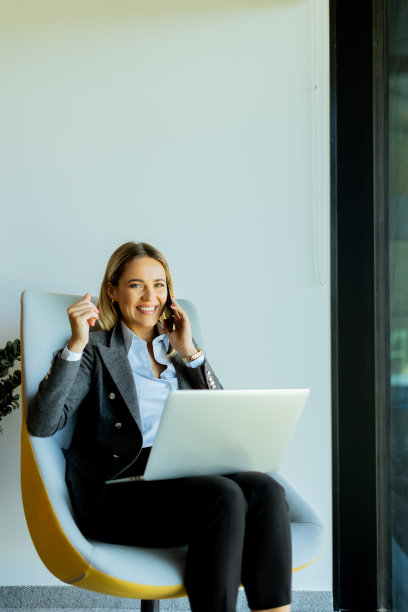 现代办公室里的女商人在白天打电话和使用笔记本电脑图片下载