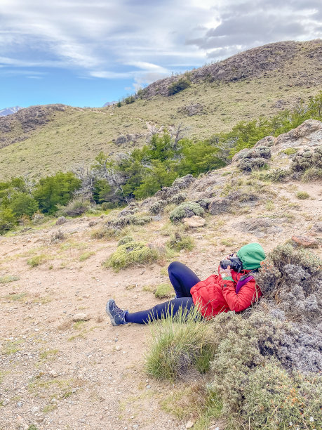 一个穿红夹克的女人躺在地上，正在拍山的照片图片下载
