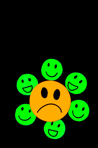 在黑色的背景上，一张悲伤的黄脸被微笑和快乐的绿脸包围着的贴纸或剪纸图片下载