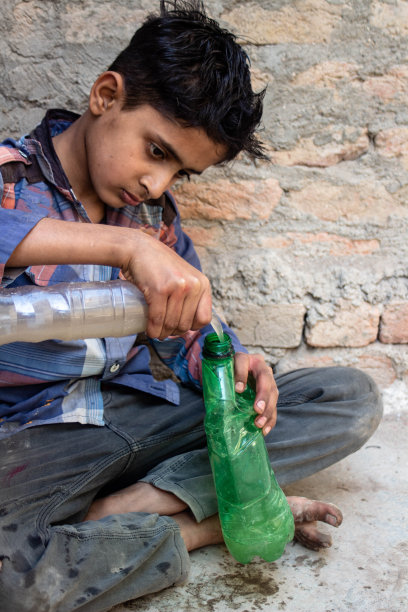 一个口渴的男孩喝着塑料瓶里的脏水图片下载