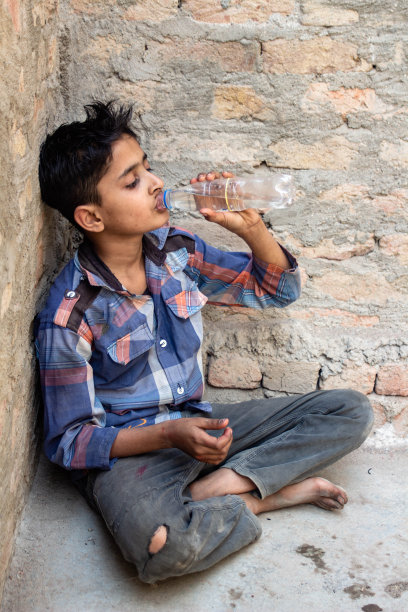 一个口渴的男孩喝着塑料瓶里的脏水图片下载