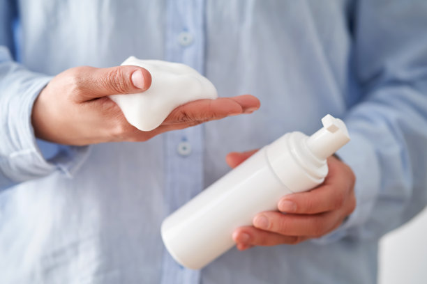 穿着蓝色衬衫的手拿着美味的面部泡沫，展示着它的质地。图片下载