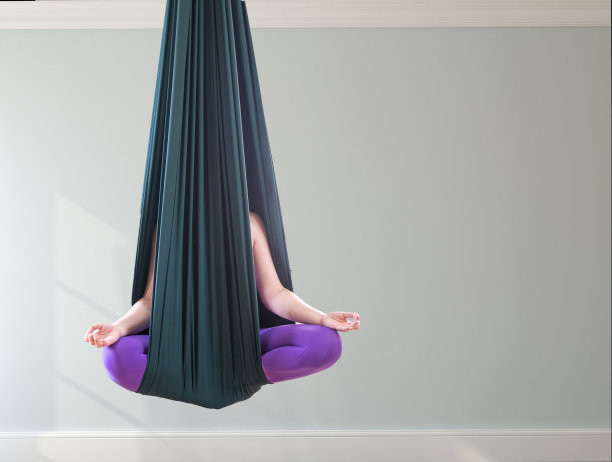 绿色瑜伽吊床。一个成年女性练习各种倒置姿势——反重力姿势，一个明亮、光线充足的工作室。这张照片是特写拍摄的，没有脸，有文字的地方。图片下载