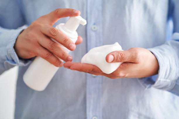 穿着蓝色衬衫的手拿着美味的面部泡沫，展示着它的质地。图片下载