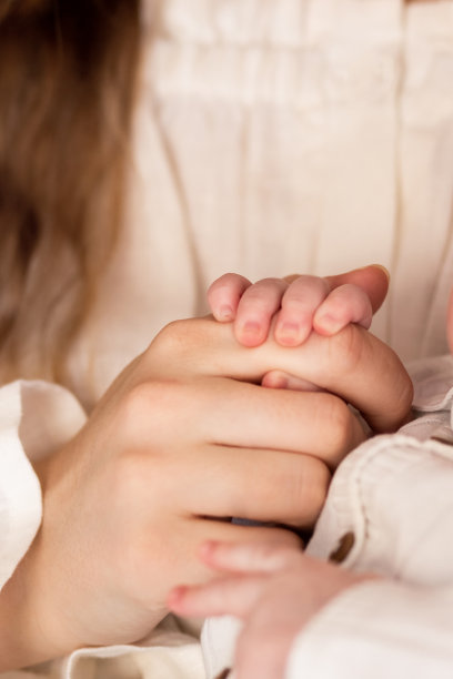 父母的手握着婴儿的小手，特写照片。家庭的概念图片下载