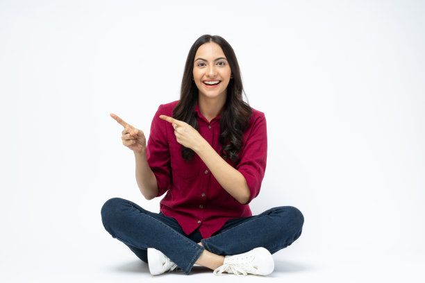 开朗可爱的女人穿着时髦的衣服，坐在地板空空间孤立的白色背景股票照片图片下载