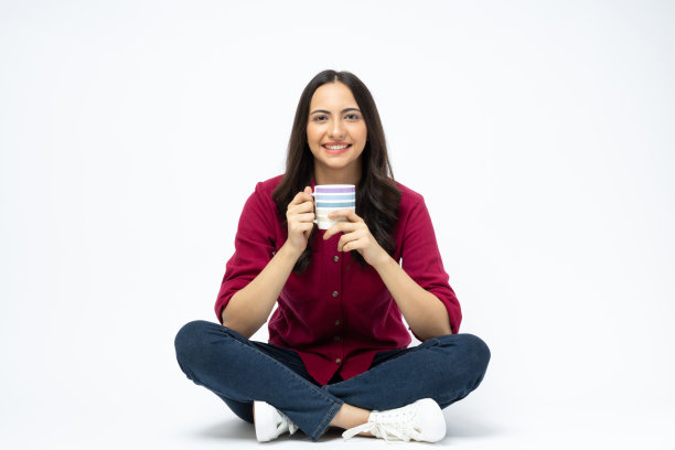 开朗可爱的女人穿着时髦的衣服，坐在地板空空间孤立的白色背景股票照片图片下载