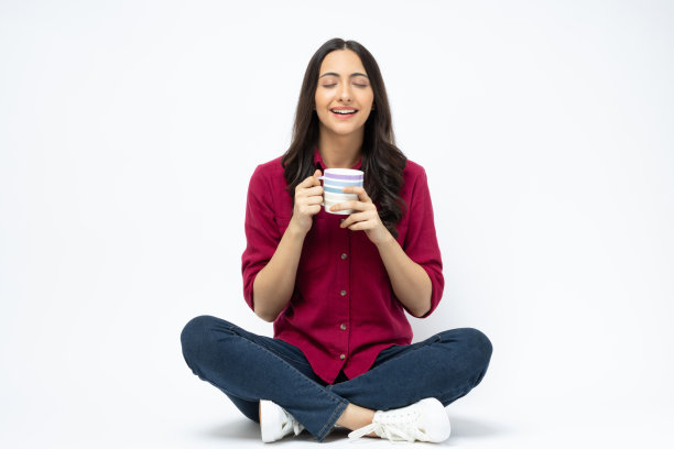 开朗可爱的女人穿着时髦的衣服，坐在地板空空间孤立的白色背景股票照片图片下载