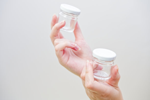 女人的手拿着装蜂蜜或液体的小玻璃瓶。图片下载