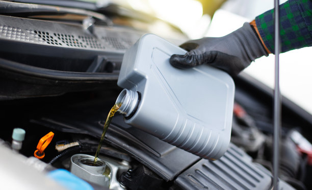 汽车机械师或修理工正在换机油的特写照片。给汽车发动机加油和倒油。传动及维修装置图片下载