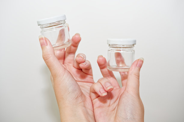 女人的手拿着装蜂蜜或液体的小玻璃瓶。图片下载