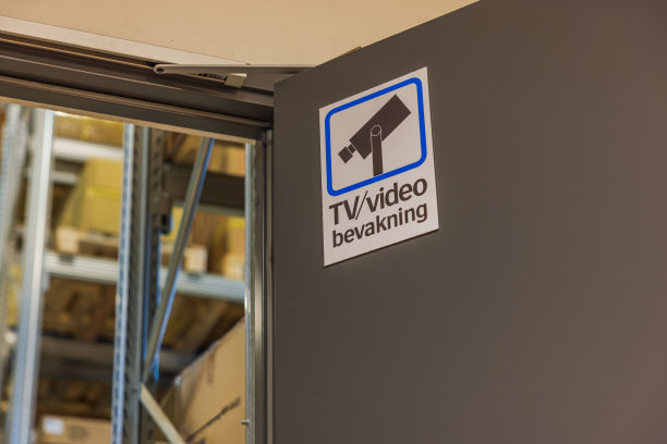 工业设施的近距离视图，仓库门上有监控标志。瑞典。图片下载