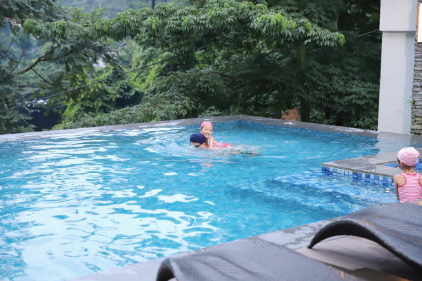 不会游泳的女儿骑在父亲的背上，让父亲带她去游泳池游泳。图片下载