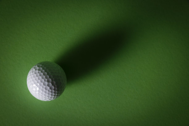 白色的高尔夫球在绿色的背景上有强烈的阴影图片下载
