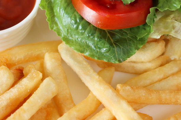 全画幅图片，一堆酥脆的薯条配上白色的鸡肉汉堡，芝麻面包汉堡包，生菜叶和番茄片，白色盘子上的番茄酱图片下载
