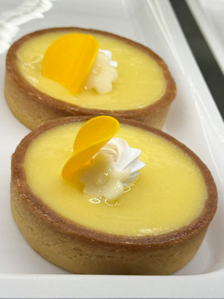 特写图片:两个独立的法式法式柠檬挞，白色托盘上的咖啡店蛋糕，短皮糕点，柠檬凝乳填充，奶油漩涡和黄色巧克力盘，重点在前景图片下载